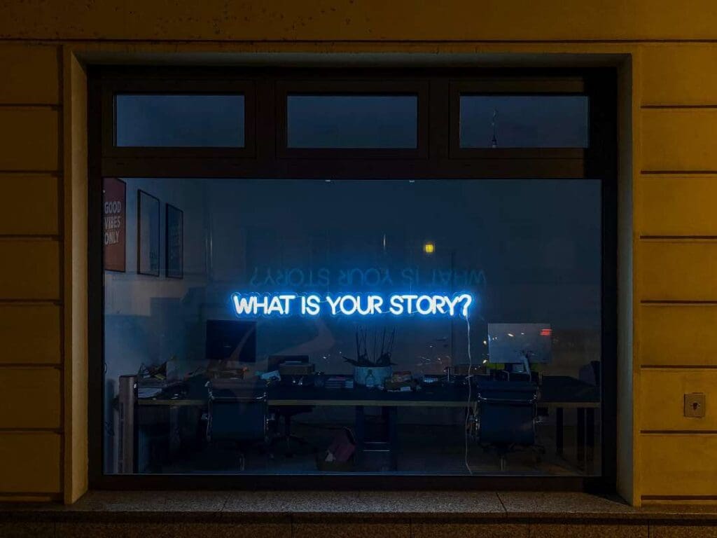 A dark window asking What is Your Story? behind which is a desk with books